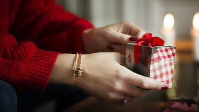 A trollbeads Christmas present being opened by a model wearing gold bangles